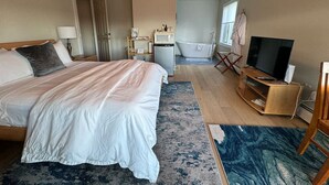 Een hotelkamer met een groot bed, een televisie, een bureau en een badkamer.