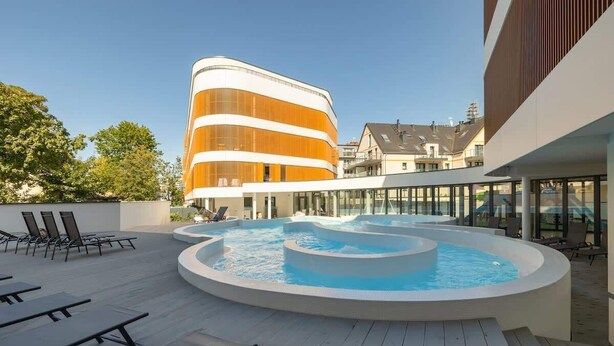 Un área de piscina en la azotea, con un edificio moderno al fondo.