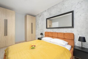 Un dormitorio con cama, mesita de noche, espejo y armarios de madera.