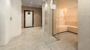 Un pasillo moderno con zona de sauna, mostrador de recepción y una puerta con la inscripción 'Entrada'.