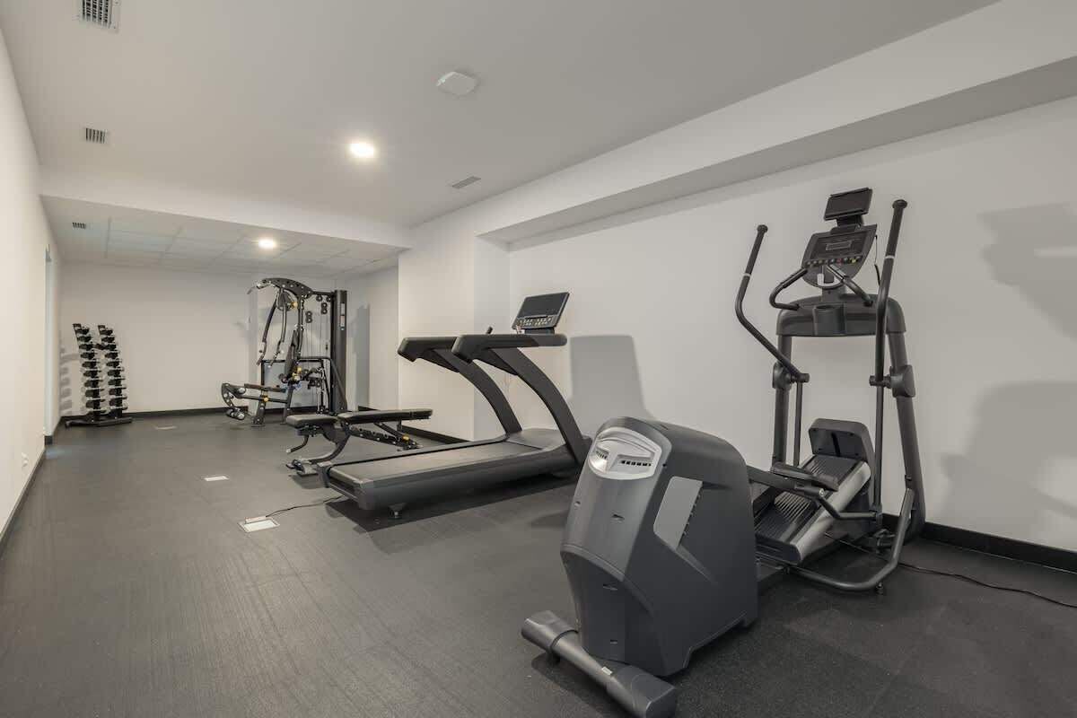 Un gimnasio con cintas de correr, elípticas y máquinas de pesas.