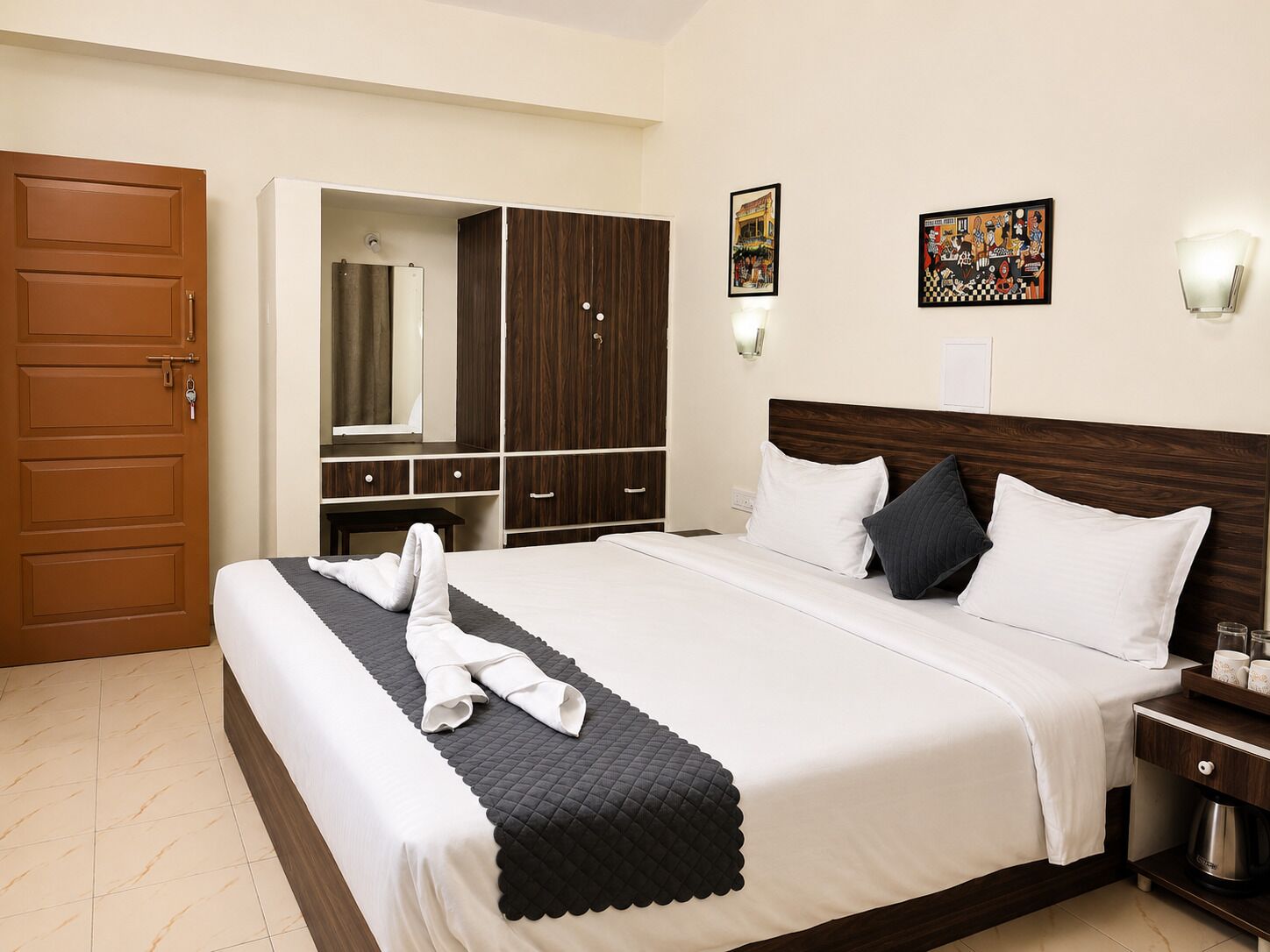 A hotel room with a bed, a wardrobe, a mirror, and two wall-mounted light fixtures.