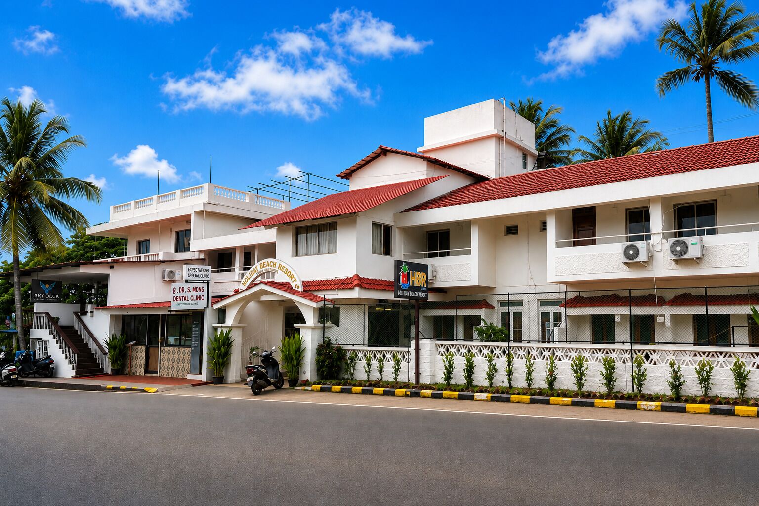 Un edificio de varios pisos con techo de tejas rojas, una clínica dental y un letrero que dice Holiday Beach Resort.