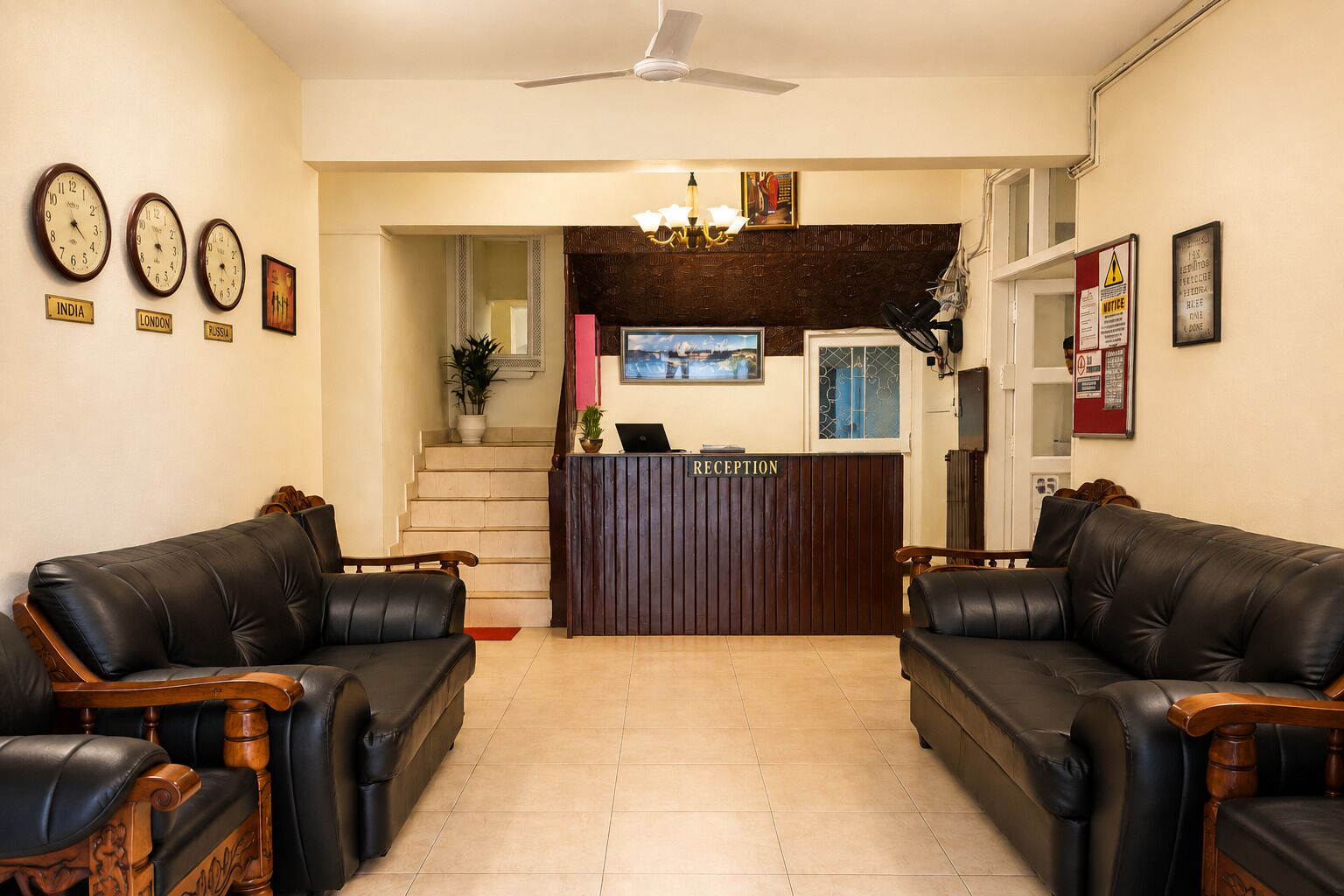 A reception area with a reception desk, two leather sofas, a ceiling fan, and clocks indicating different time zones.