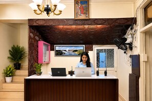 En receptionsdisk med två bärbara datorer, en inramad tavla och en kristallkrona.