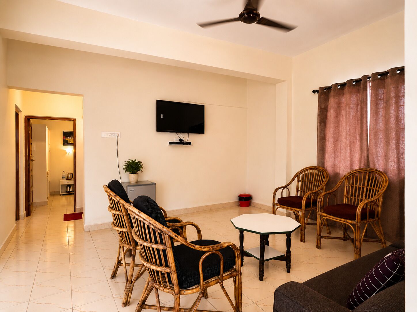 Una sala de estar con televisión, dos sillones de mimbre, una mesita y un sofá.
