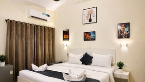 A hotel room with a bed, bedside tables, a wall-mounted air conditioner, and artwork. - Holiday Beach Resort (Candolim)