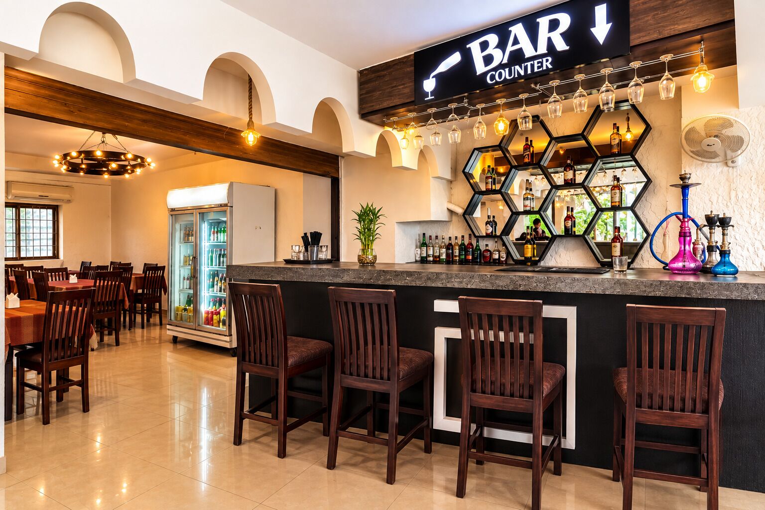 Un espace bar comprenant un comptoir, des tabourets de bar et une variété de bouteilles et de verres.