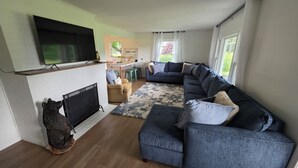 Una sala de estar moderna con un sofá seccional, una chimenea y un televisor montado en la pared.