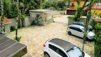 Zona residencial con un camino pavimentado, coches aparcados y un pequeño edificio con techo inclinado.