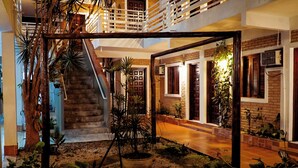 Un interior de varios niveles con escaleras, piso de madera y plantas en macetas.