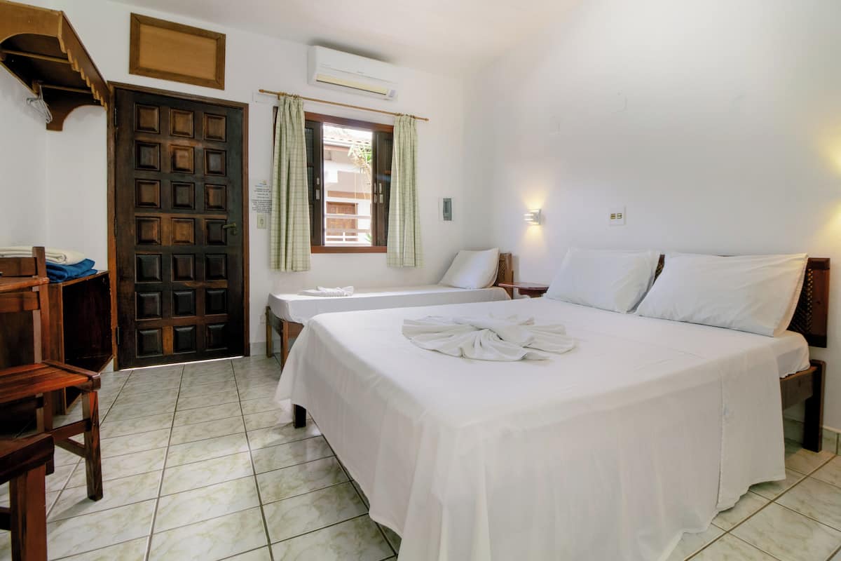 A bedroom with two beds, a wooden desk, and a window with curtains.