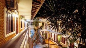 Un espacio interior de varios niveles con una escalera central, rodeado de paredes de ladrillo y barandillas de madera.