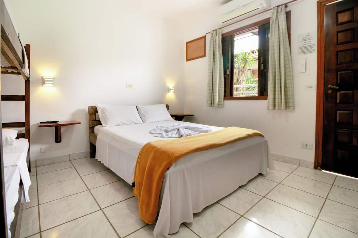 A bedroom with a bed, bedside tables, a window with curtains, and a door.