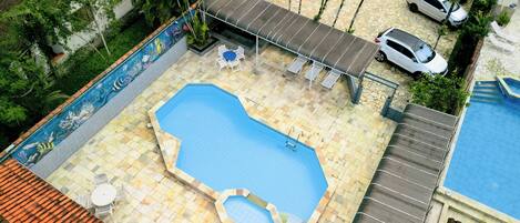 Una piscina en la azotea con un toldo, un jacuzzi pequeño y un espacio de estar con sillas.