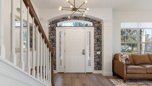 A hallway with a wooden staircase, a white door with glass panels, and a patterned wall. - Hilltop 6BR Disney Villa: Theater, Pool/Spa, View (Kissimmee)