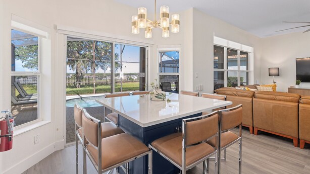 A modern kitchen with a large island, dining area, and a living room with a sofa. - Hilltop 6BR Disney Villa: Theater, Pool/Spa, View (Kissimmee)