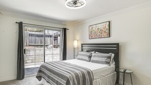 A bedroom with a bed, a bedside table, a lamp, a window with curtains, and a ceiling fan. - Poway Retreat w/ Stunning Sunset & Mountain Views! (Poway)