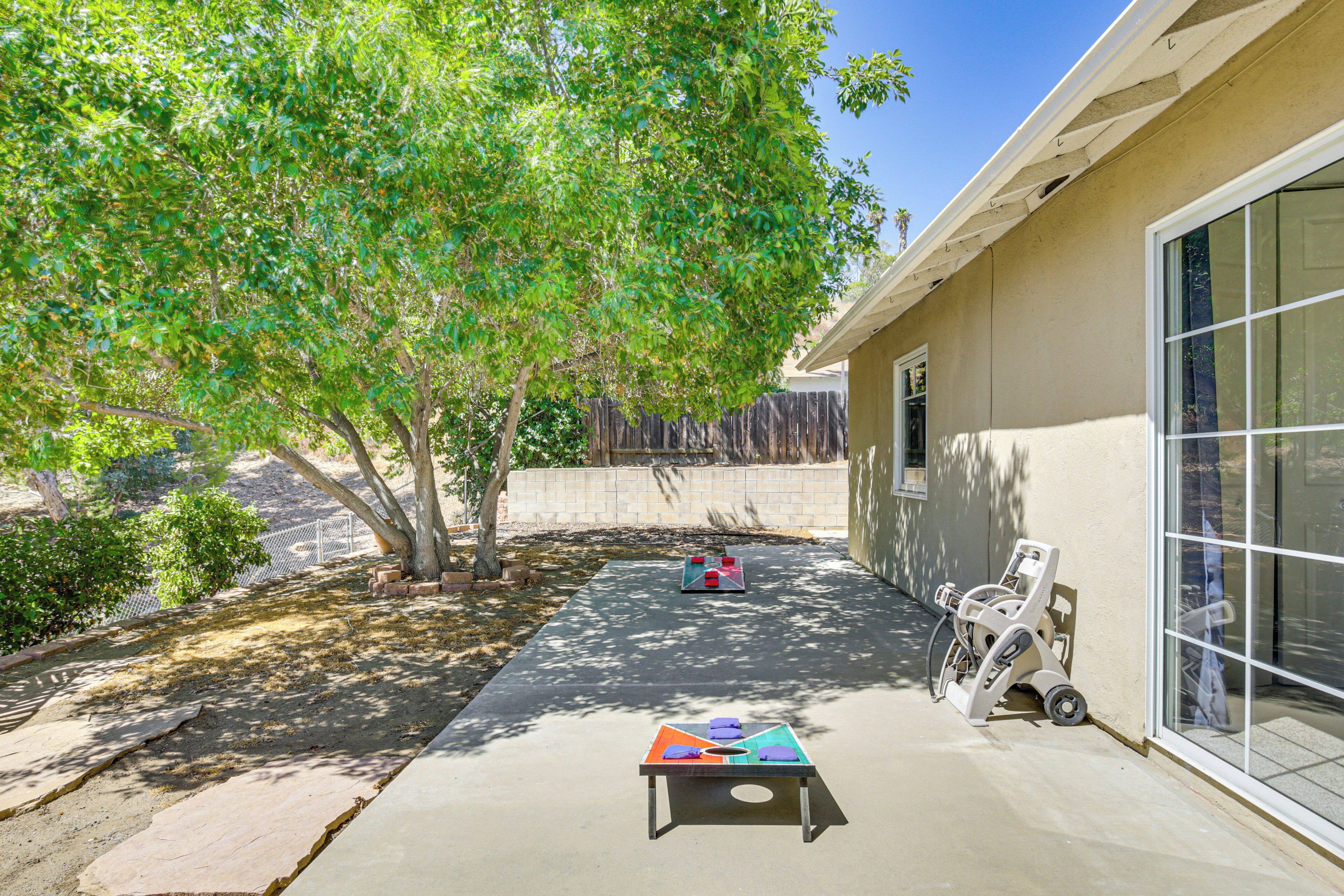 A patio area with a table and chairs, a tree, and a building with a window.