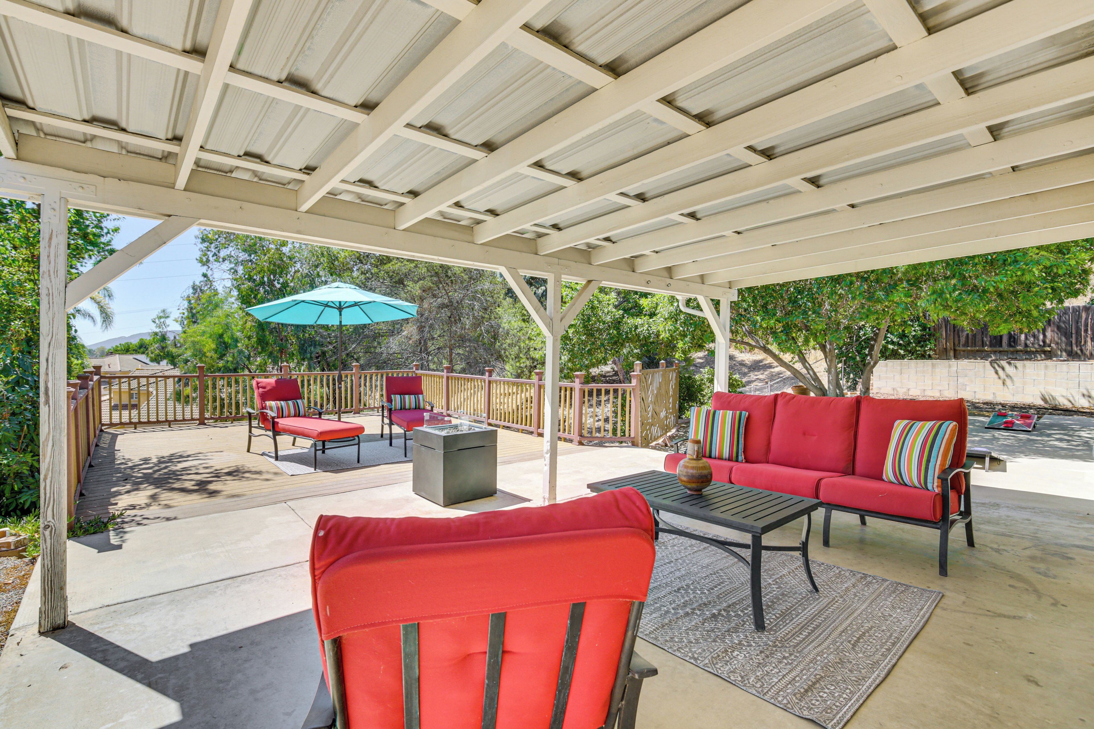 A covered patio area with outdoor furniture, including a red sofa and chairs, and a table.