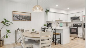A modern kitchen with white cabinets, a central island, and a dining area with a round table and chairs.