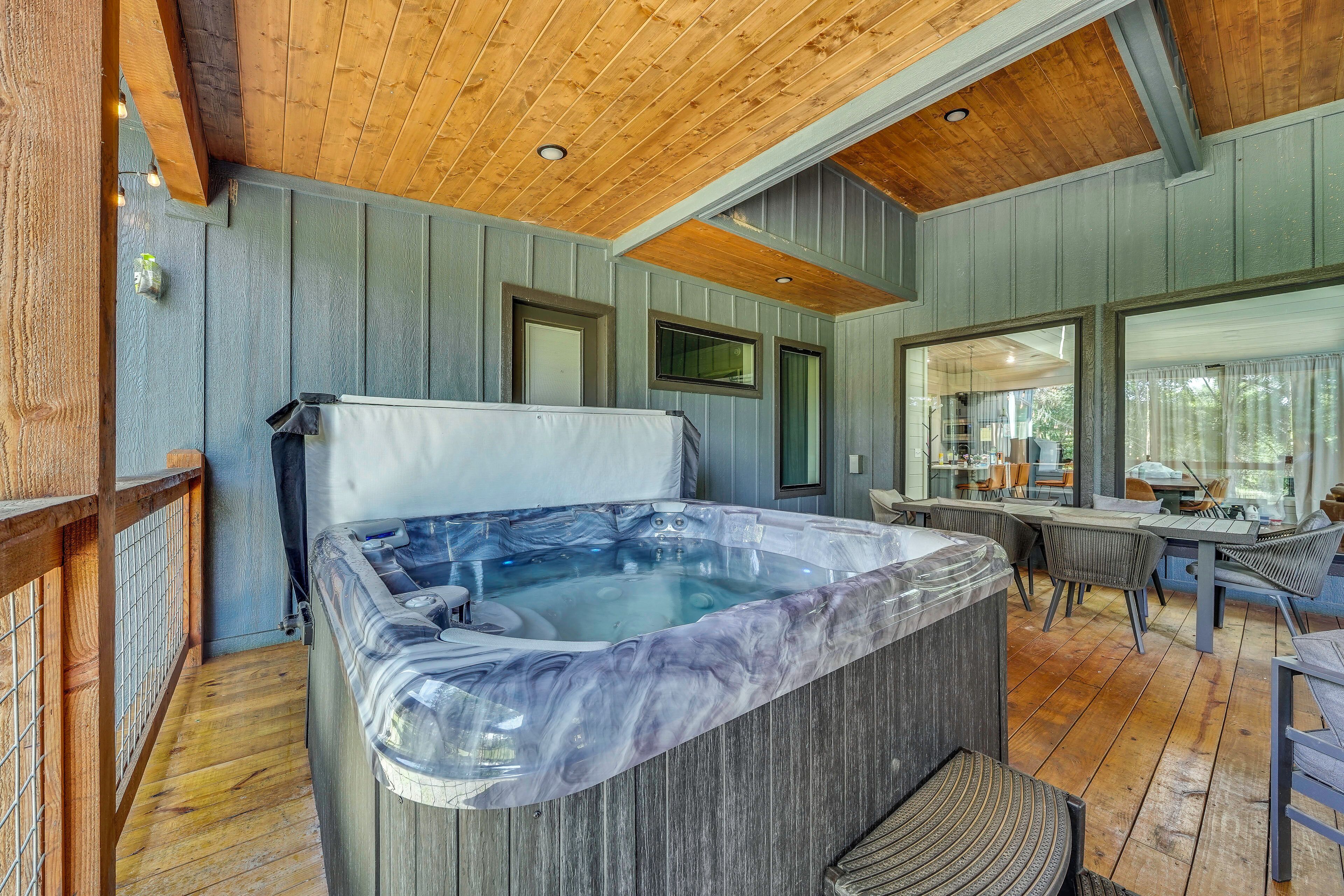 A hot tub in a wooden deck area with a dining table and chairs.