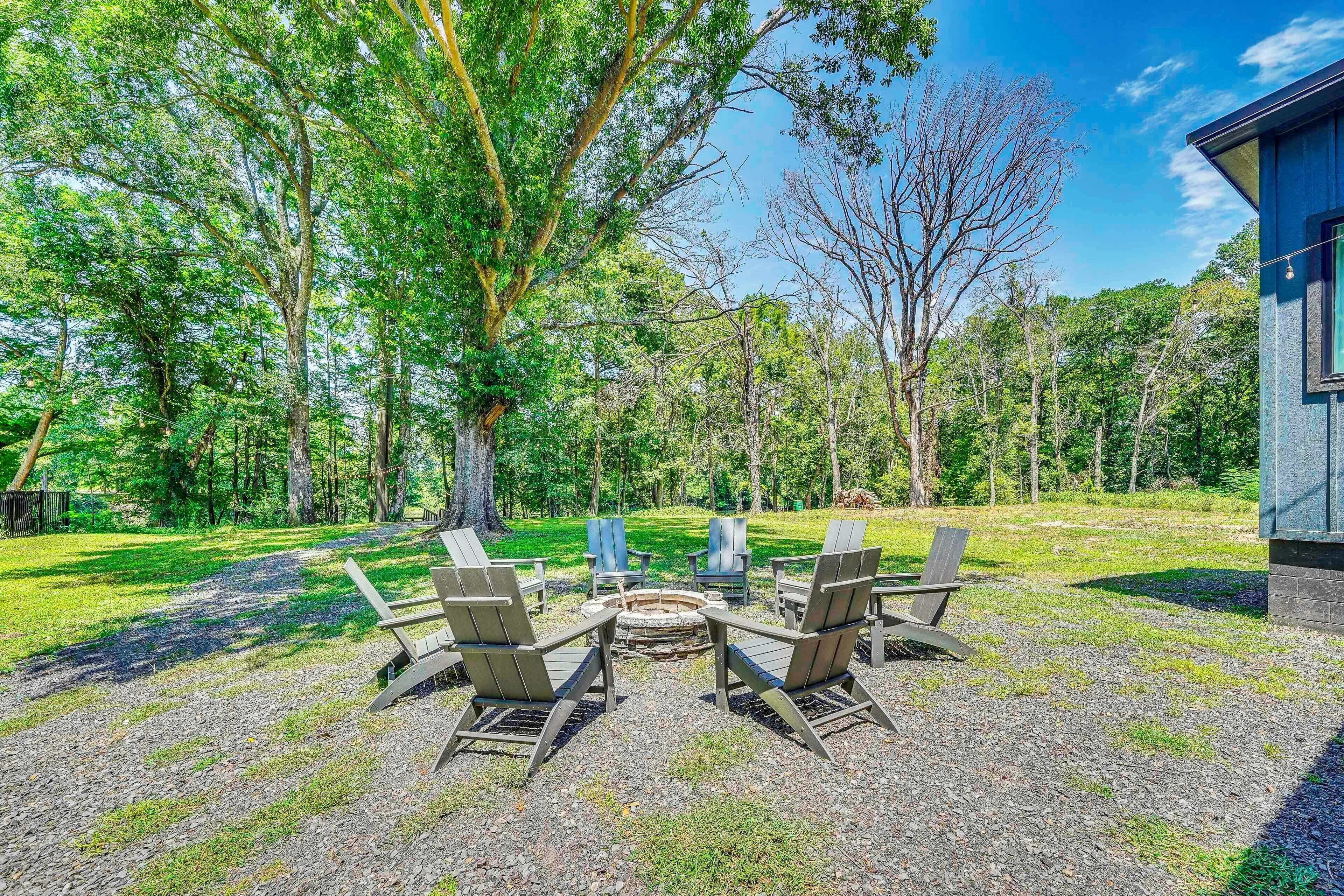 Et udendørs siddeområde med Adirondack-stole og et bålsted.