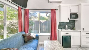 A modern kitchen with white cabinets, a built-in microwave, and a small refrigerator.