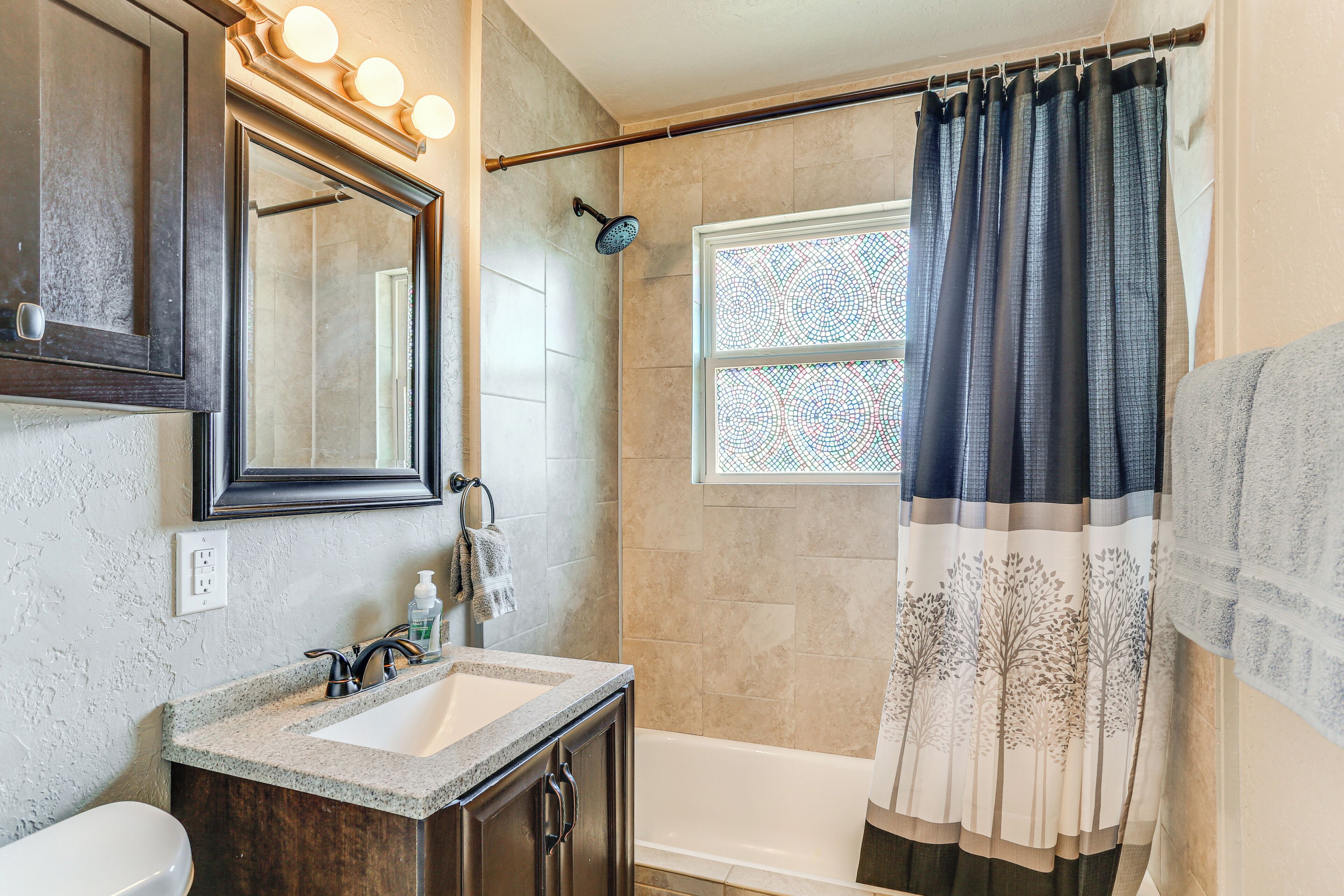 A bathroom with a sink, mirror, and shower.