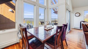 A dining area with a wooden table and chairs, large windows, and a view of the outdoors. - Luxury Modern Retreat: 40 Acres and Mountain Views (Glenwood Springs)