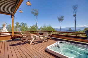 A wooden deck with outdoor seating and a hot tub, overlooking a scenic landscape with trees and mountains. - Luxury Modern Retreat: 40 Acres and Mountain Views (Glenwood Springs)