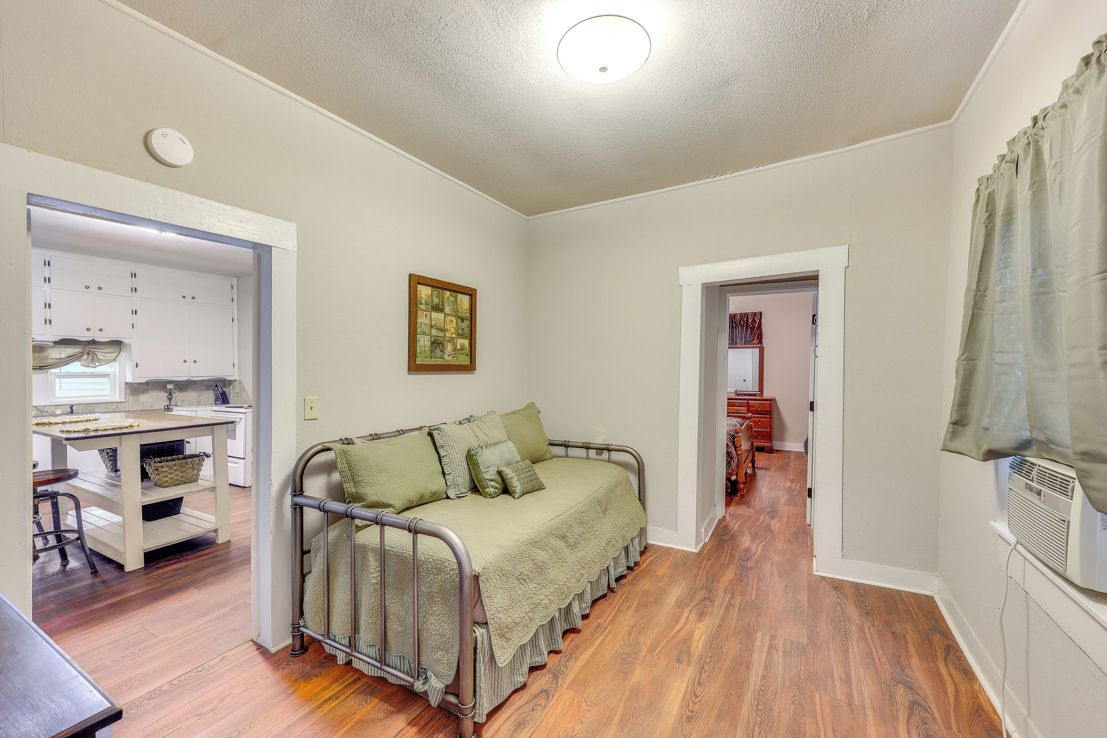 A compact living space with a kitchenette, a metal-framed sofa, and a dining area.