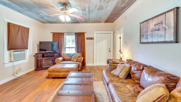 A living room with a wooden ceiling, a ceiling fan, a television, leather sofas, and a painting on the wall. - Near Talimena State Park: Quiet Talihina Getaway (Talihina)