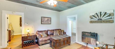 A spacious living room with a leather sofa, wooden coffee table, and a ceiling fan.