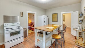 A compact kitchen with a stove, oven, and refrigerator. There is a wooden table with chairs and a small bar stool. - Near Talimena State Park: Quiet Talihina Getaway (Talihina)