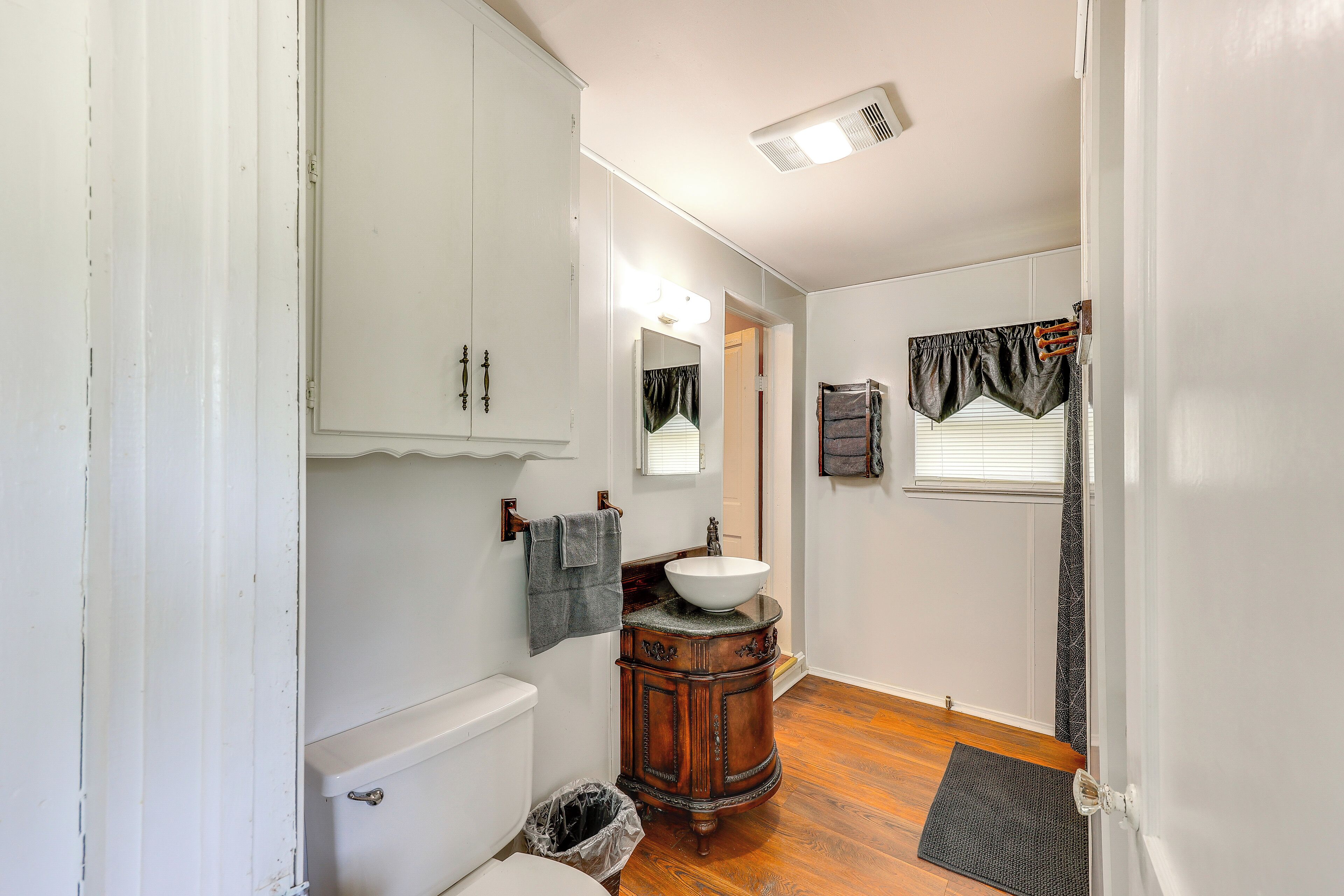 A bathroom with a white toilet, wooden vanity, and a sink.