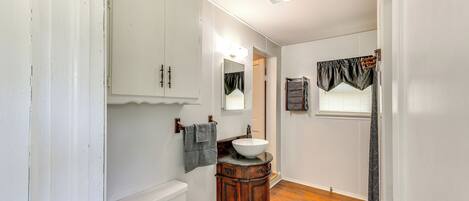 A bathroom with a white toilet, wooden vanity, and a sink.
