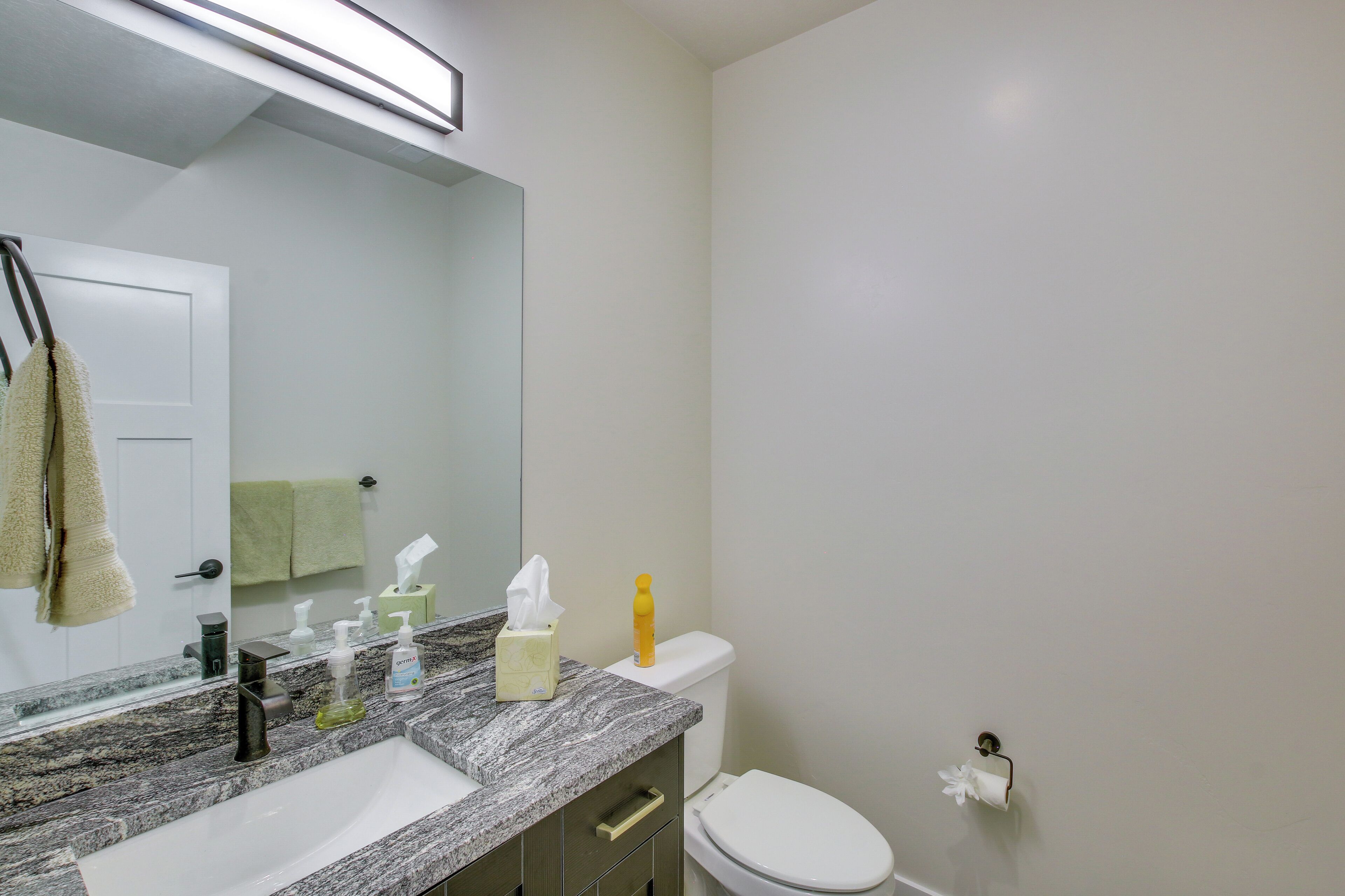 A bathroom with a marble sink, a mirror, a toilet, and a towel rack.