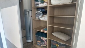A walk-in closet with shelves, storage bins, and a folded blanket.