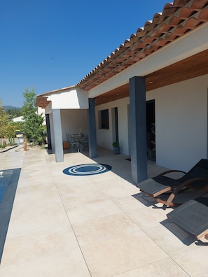 A covered outdoor area with a tiled floor, a circular design, and a lounge chair. - Villa Plain Pied (Fayence)