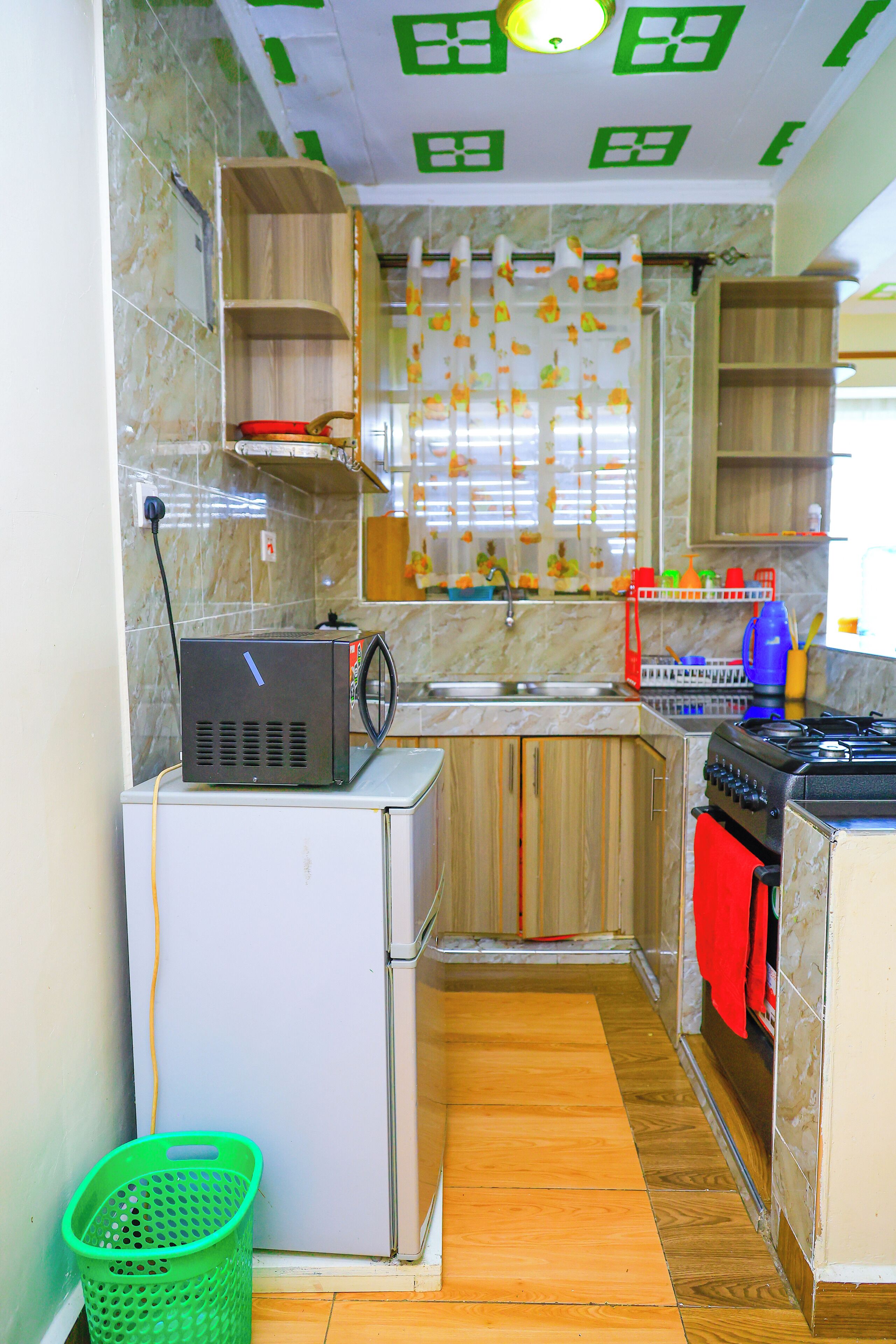 A compact kitchen with a refrigerator, stove, and wooden cabinets.