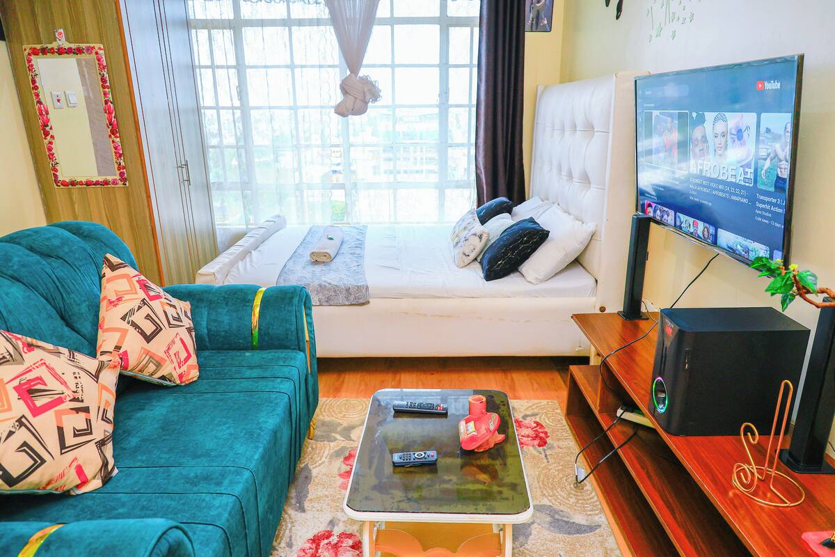 A bedroom with a bed, a TV, a coffee table, and a sofa.