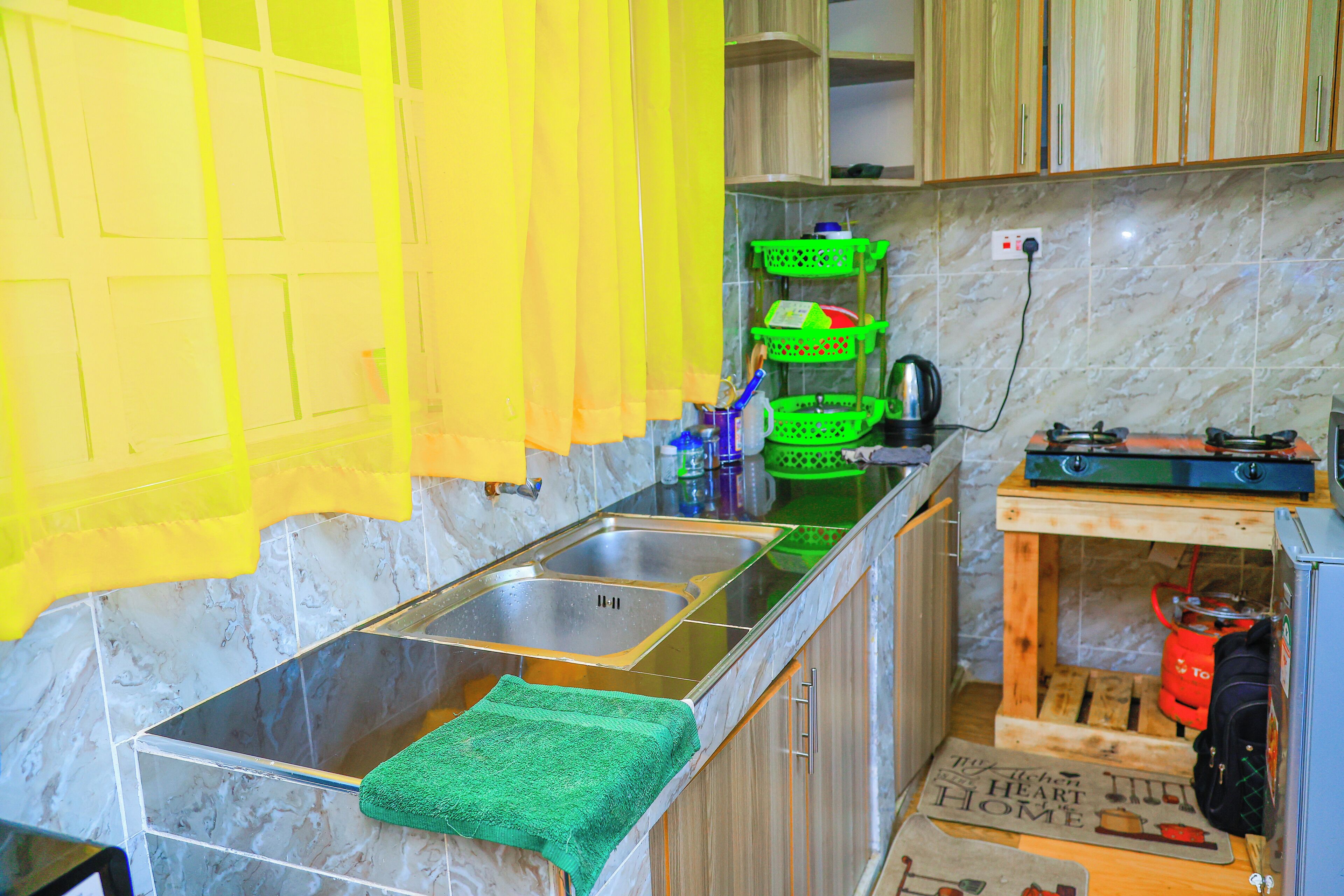 A kitchen with a marble countertop, a sink, and a wooden cabinet.