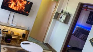 A living room with a flat-screen TV, a small round table, and a sofa. - Lux Suites Three Unit Complex Ruiru (Ruiru)