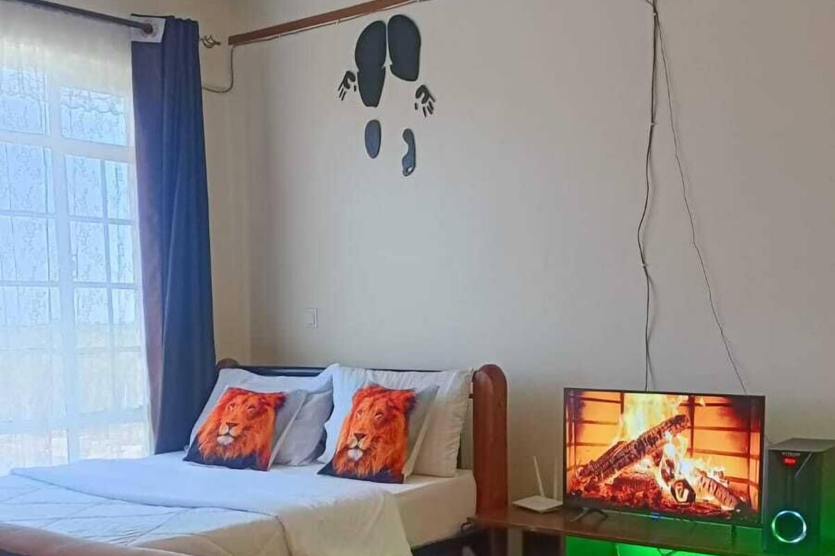 A bedroom with a bed, a television, and a green gaming chair.