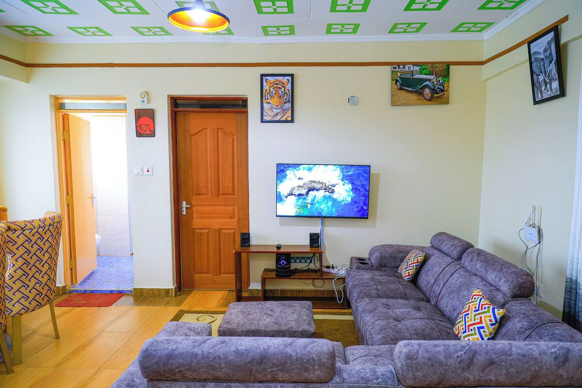A living room with a sofa, a television, and a wooden door.