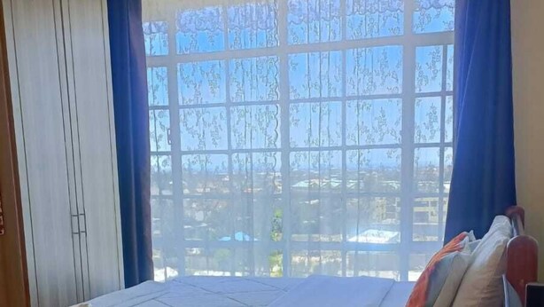 A room with a bed, a small table, a sofa, and a TV. - Lux Suites Three Unit Complex Ruiru (Ruiru)