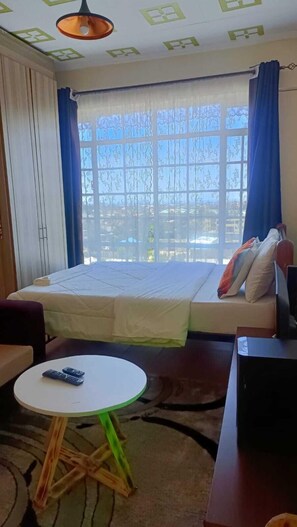 Una habitación con una cama, una mesita pequeña, un sofá y un televisor.