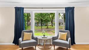 A room with two grey armchairs, a small round table, and a window with blue curtains.