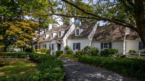 A row of white houses with dark shutters, surrounded by lush greenery and a gravel path. - Minutes from Downtown St. Michaels | Pool | Cabana | Kayaks | Private Dock (St. Michaels)